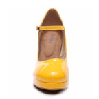 A front view shows the Claudia shoe, a yellow vegan patent Mary Jane with an ankle strap and street sole. Its interior, including insole, is visible. The closed-toe design has a chunky high heel for bold elegance.