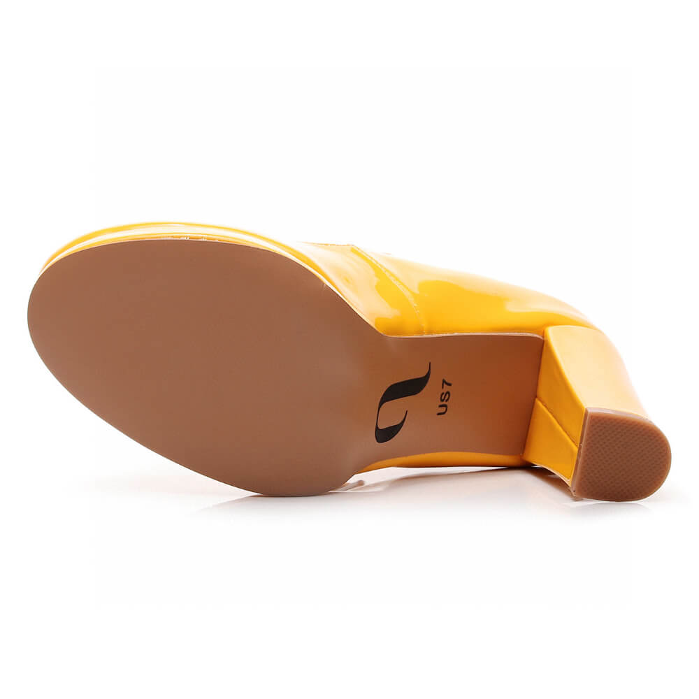 The Claudia Yellow Vegan Patent heel lies on its side, revealing a shiny surface and the street sole. The chunky high heel looks sturdy, and a size marking is visible on the sole.