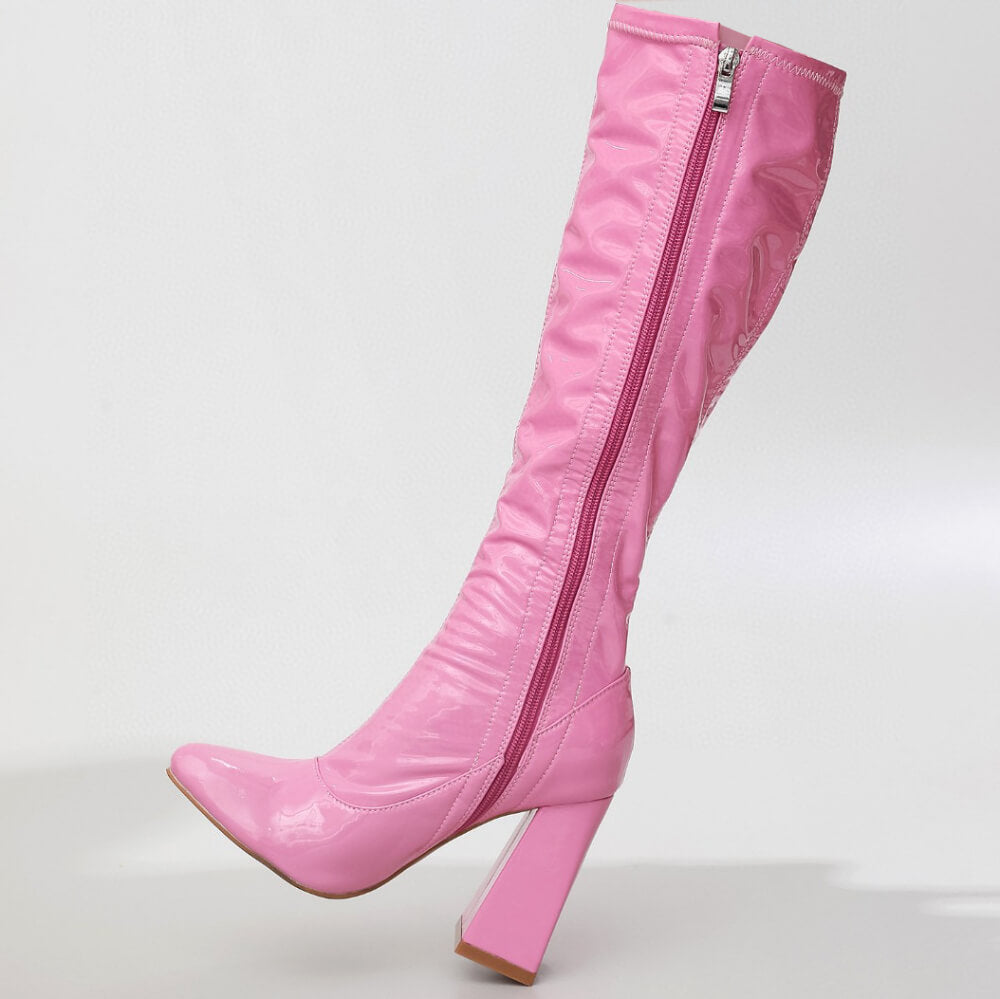 The La Gogo Calf Boot - Pink Wet Look - Street Sole is a shiny pink knee-high boot made from stretch vegan patent with a high block heel and a side zipper, elegantly displayed against a plain white background.