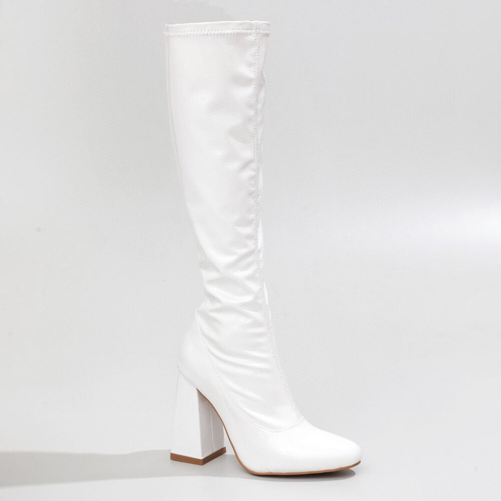 The La Gogo Calf Boot in White Wet Look showcases a chic knee-high silhouette with a chunky block heel. Crafted from vegan patent material, it features a smooth, shiny finish with a rounded toe, exuding minimalist elegance against a light gray background.